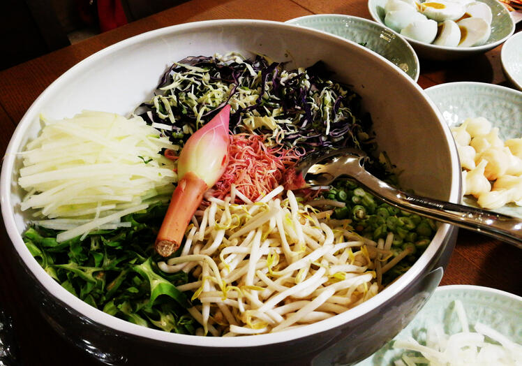 A bowl of fresh herbs and vegetables prepared as accompaniments for nasi kerabu.