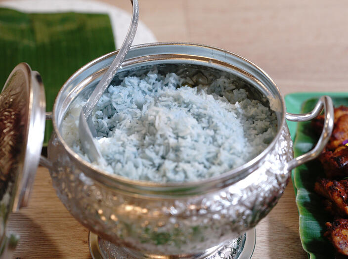 Blue pea flower rice served in an ornate metal serving bowl.
