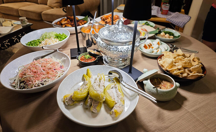 A communal Warisan table laid with nasi kerabu, vegetables, condiments, grilled dishes and shared accompaniments.