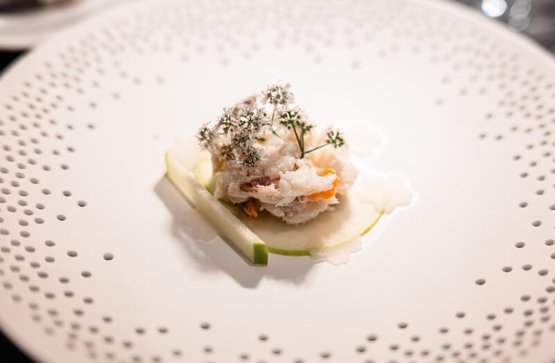 Blue swimming crab with green apple and coriander flowers on a white ceramic plate.